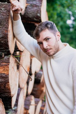 Tahta kütüklerin yanında genç bir adamın portresi. Model, doğa, endüstri, şirket ve ahşap konsept.