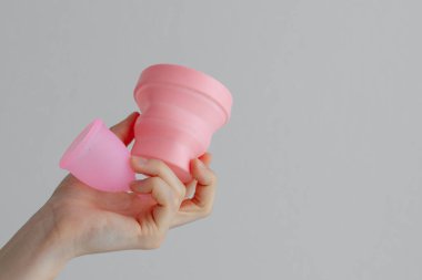 Pembe bir adet bardağının üst görüntüsü ve beyaz bir arka planda dezenfeksiyon için bir kap. Kadınsı mahrem hijyen ürünü, kan toplama kabı.