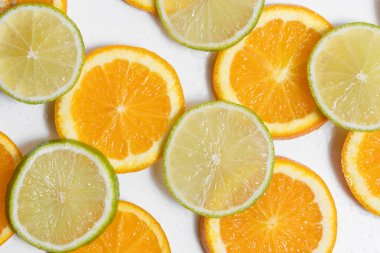 Su damlalarıyla kaplı beyaz bir zeminde turuncu ve limon dilimleri bulunuyor. Tasarımınız için arkaplan