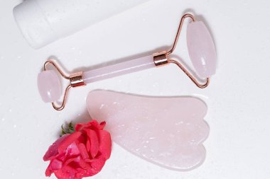 Guasha masaj aleti ve beyaz izole arkaplanda yüz kremi.