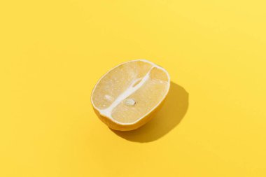 Fresh lemon illuminate by hard light lying on yellow isolated background close-up.