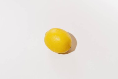 Yellow lemon illuminated by harsh daylight on a white isolated background. Image for your design. Ingredient for cometics