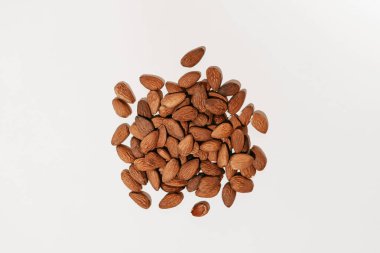 Almond nuts scattered on a white isolated background illuminated by hard light. Image for your design or mockup