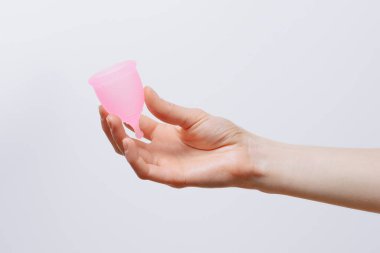 Beyaz izole edilmiş arka planda pembe regl bardağını tutan bir kadın. Hijyen ürünleri, kadın adet döngüsü ve ekolojik alternatif kavram.