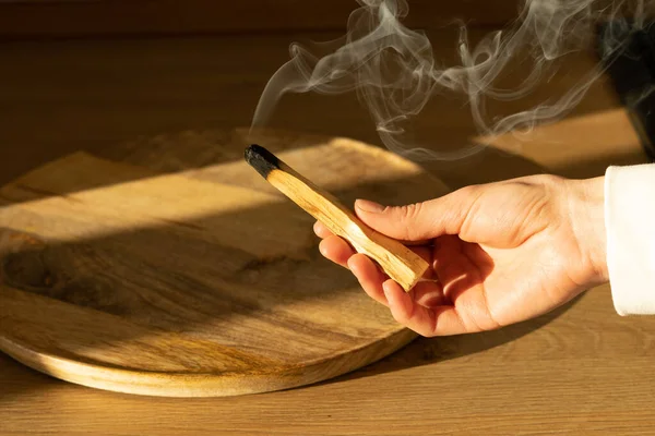 Bir kadının eli kutsal palo santo ağacının tüten bir çubuğunu tutuyor. Kutsal ibiocai ile ayin, meditasyon, tütsülenmiş aromaterapi.