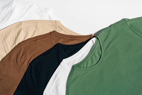 stock image White, beige and green t-shirts laid out on a white isolated background. The concept of choosing clothes and replacing the wardrobe