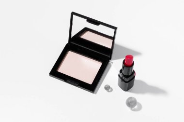 Aynalı kadın pudrası ve beyaz izole arkaplanda kırmızı ruj. Güzellik ve estetik kavramı, makyaj ürünleri..