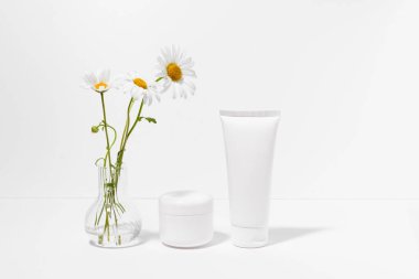 Beyaz izole arkaplanda papatya özütü bulunan beyaz doğal yüz kremi tüpü. Kavram, güzellik, cilt bakımı