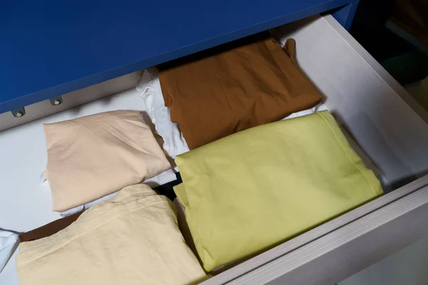 Close up of the clothes are neatly folded in the drawer of the wardrobe. The concept of compact storage and tidying up the room