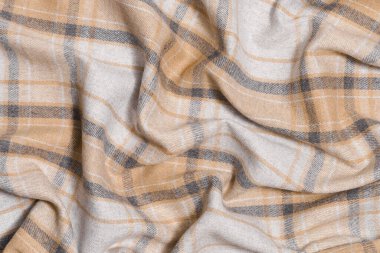 Bej ve gri renkte buruşmuş ekose kumaş dokusu. Geleneksel İskoç kıyafetleri. Gömlekler ve etekler için malzeme.