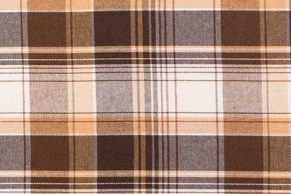 Kahverengi ve fildişinin yakın çekim dokusu tartan kumaşı kontrol etti. Geleneksel İskoç kıyafetleri. Gömlek ve etek yapmak için malzeme