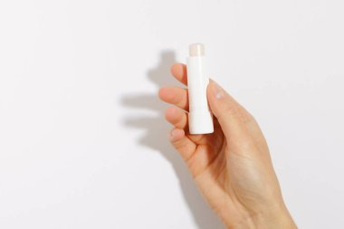 Beyaz izole edilmiş arka planda, kadın eli temiz koruyucu dudak merhemi tutuyor. Tasarımın için bir model. Sağlık ve güzellik için dekoratif kozmetik kavramı