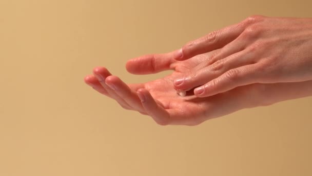 여자는 손가락으로 손바닥에 크림을 베이지색 배경에 문질러 화장품 — 비디오