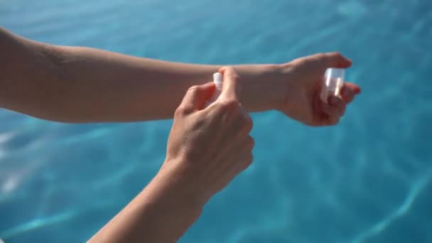 女性の手は プール内のスパークリング水の背景に対して 皮膚の瓶から血清または保湿油を適用します 日焼け止め 水和肌 天然化粧品のコンセプト — ストック動画