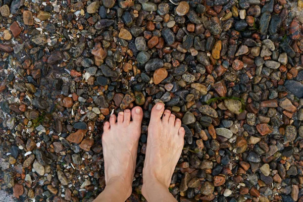 Wet feet of young woman on stones near sea or ocean water on beach. The concept of foot massage, rest or vacation by the sea, on the Mediterranean Sea