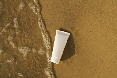 Islak kumda deniz dalgası ile nemlendirici ve besleyici cilt kreminin beyaz modeli. Vücut veya yüz için kozmetik konsepti. UVA koruması