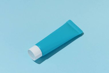 Mavi bir yüz maskesi ya da doğrudan ışıklandırmalı mavi izole bir arka planda göz kremi. Güzellik ürünleri kavramı cildini nemlendirir ve besler.