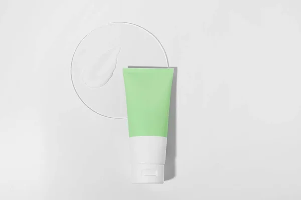 Green and white cream tube mockup and smear sample on glass on white isolated background. Concept of beauty products, skin care, moisturizing and restoration