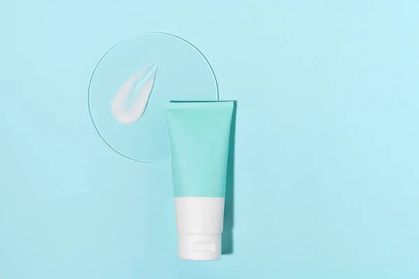 Blue and white mockup tube of cream moisturizer and smear sample on glass on blue isolated background. Concept of beauty products and facial skin care