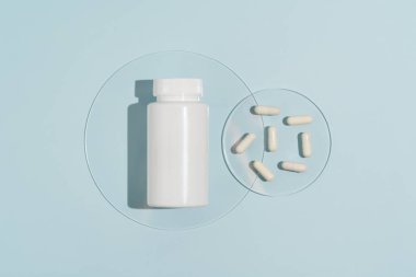 Beyaz model boş kavanoz ve mavi izole arka planda duran doğal haplar. Eczane, ilaç, beslenme malzemeleri, antibiyotikler ve antidepresanlar. Tasarımın için resim