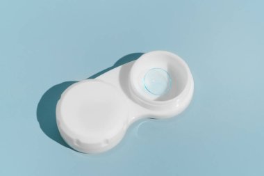 Mavi izole arka plandaki konteynırdaki göz görüşünü iyileştirmek için mavi yumuşak kontakt lens. Optalmoloji kavramı, göz tedavisi