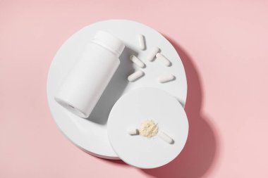 Beyaz kapsül hap kavanozu ve kabuk modeli. Pembe izole arka plandaki kaidede aktif bileşen var. Sağlık, ilaç, eczane ve beslenme takviyeleri kavramı