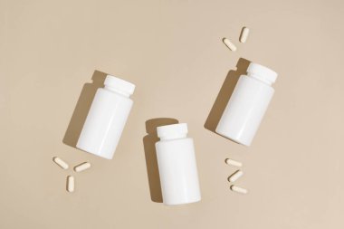 Bej izole arka planda üç beyaz maket kavanozu ve hap kapsülü. Eczane, ilaç, sağlık, bilimsel tıbbi araştırma ve ilaveler kavramı