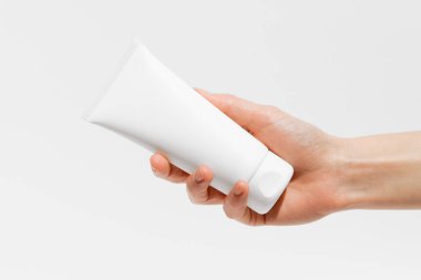 Beyaz izole edilmiş arka planda beyaz krem tüplü bir kadın. Güzellik ürünleri, kozmetoloji konsepti