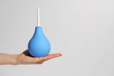 Beyaz izole arka planda mavi kauçuk lavman tutan kadın eli. Tıbbi prosedürler, detoks ve vücut temizliği kavramı, sağlık hizmetleri. tasarımınız için resim