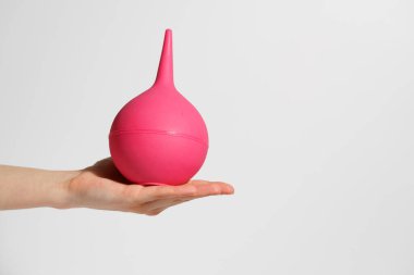 Beyaz izole edilmiş arka planda pembe lavman tutan bir kadın. İlaç, prosedür, detoks ve vücut temizliği kavramı, sağlık konuları.