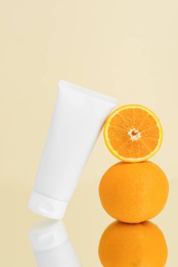 İki portakallı beyaz krem tüp modeli ve bej izole arka planda yansıması. Güzellik, yüz ve vücut bakımı kavramı