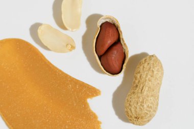 Fıstık ezmesinin yakın çekim dokusu ve beyaz yalıtılmış arka planda kabuklu ceviz. Doğal yiyecek kavramı, sağlıklı atıştırmalık, protein.