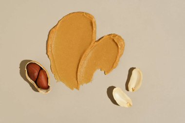Bej izole arka planda fıstık ezmesi ve fıstık ezmesi kreması lekesi. Protein kaynağı, sağlıklı atıştırmalık, fındık ezmesi konsepti..