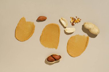 Kremalı fıstık ezmesi ve kabuklu fındık parçalarının bej izole arkaplanının üst görüntüsü.