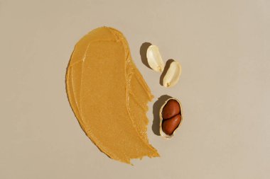 Fındık ezmesinden yapılmış kahverengi fıstık ezmesi dokusu ve bej izole edilmiş bir arka planda fıstık parçaları. Doğal fındık ezmesi kavramı, sağlıklı protein atıştırmalıkları.