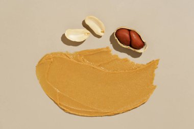 Krema lekeli kahverengi fıstık ezmesi ve bej izole edilmiş arka planda fıstık ezmesi. Protein besin konsepti, doğal bileşenler.