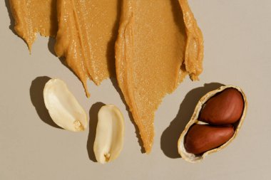 Fıstık ezmeli kremalı ve bej izole arkaplanlı kabuklu, yakın çekim lekeli fıstık ezmesi. Doğal fındık tatlısı konsepti, protein atıştırmalıkları.