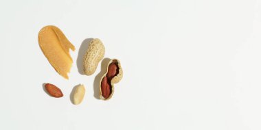 Kahverengi fıstık ezmesi ve beyaz izole edilmiş arka planda yer fıstığı karışımı. Protein atıştırmalığı kavramı, doğal tatlılar. Pankart tasarımınız için arkaplan