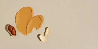 Kremalı fındık ezmesi ve bej izole arka planda yer fıstığı. Protein kaynağı, sağlıklı atıştırmalık, fıstık ezmesi konsepti. Pankart tasarımın için arka plan. Metin için yer