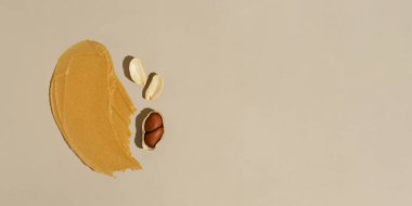 Bej izole arka planda fıstık ezmeli ve kabuklu kremalı kremalı fındık ezmesinin yakın çekim lekesi. Doğal fındık tatlıları, protein atıştırmalıkları. Pankart tasarımınız için arkaplan.