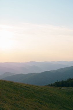 Şafağın dikey görüntüsü ve güneş tarlada ve dağlarda parlıyor. Tasarımınız için resim ve metniniz için boşluk