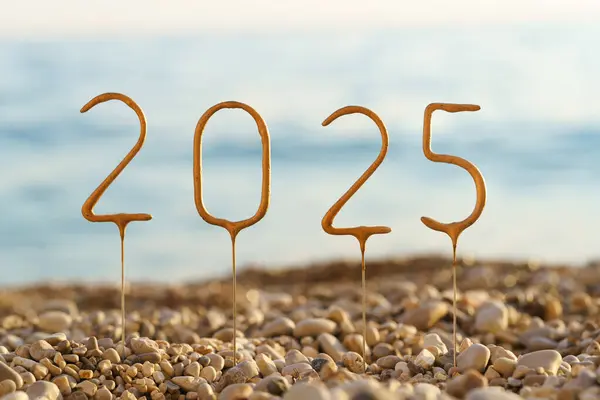 Deniz suyunun arka planında 2025 yıllık çakıl taşları ve sahilde gün batımına yakın çekim. Mutlu yıllar, başarı ve refah dileklerim, tebrikler, kutlamalar, tebrik kartları