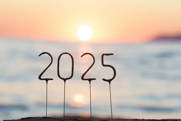 Güneşin arka planında 2025 numara deniz ve gün batımında yansımalarla birlikte. Yeni yıl ve Noel için selamlama kavramı, kutlama, sevinç, başarı ve ilham dilekleri