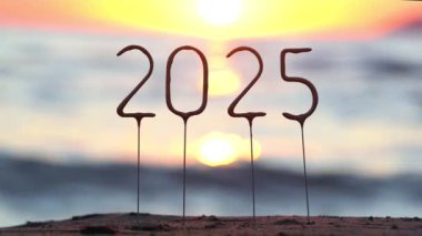 Deniz suyunun arka planında 2025 yıl ve sahilde gün batımında altın sayılar. Meslektaşlarımıza ve arkadaşlarımıza mutlu yıllar, başarı ve refah dileklerimiz, tebrikler, kutlamalar, tebrik kartları.