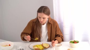 Gömlekli genç bir kadın evde körili pilav ve beyaz masalı salatayla yemek yiyor. Ev yapımı yemek, sağlıklı beslenme, besleyici beslenme