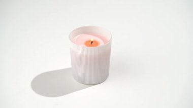 Camdaki pembe mumun beyaz izole arkaplanda yanan fitili yakın plan. Samimiyet, ev ve iç dekorasyon, kutlama, meditasyon ve rahatlama konsepti