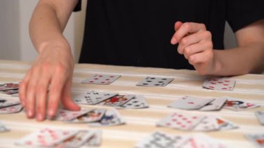 Masada solitaire oynarken kart seçen ve istifleyen genç bir kadının elleri. Eğlence konsepti, eğlence, kart oyunları, poker