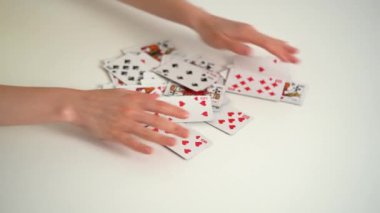 Genç bir kadının elleri beyaz bir masadan kart toplar ve bir sonraki oyun için onları karıştırır. Eğlence konsepti, eğlenme, kart oyunları
