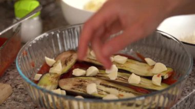 Genç bir kadın dilimlenmiş mozzarellayı bir tabağa koyar ve mutfakta klasik parmesan peyniri hazırlarken üzerine parmesan serpiştirir. Ev yemeği, sağlıklı beslenme, taze sebze.