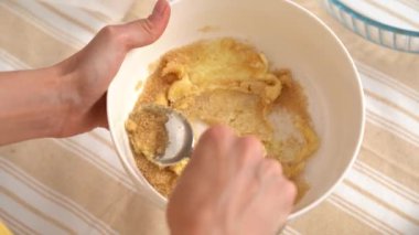 Genç bir kadının ellerinin, kurabiye ya da kek hazırlamak için bir kaşık ile tereyağlı esmer şekeri karıştırdığı yakın plan. Evde yemek pişirme malzemesi kavramı, aşçılık hobisi